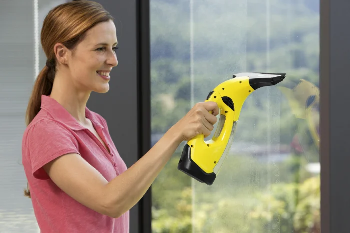 Person reinigt Fenster mit elektrischem Fensterreiniger